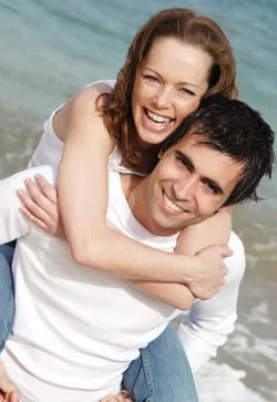 Young couple smiling. Dental insurance may cover your treatment, find out more.